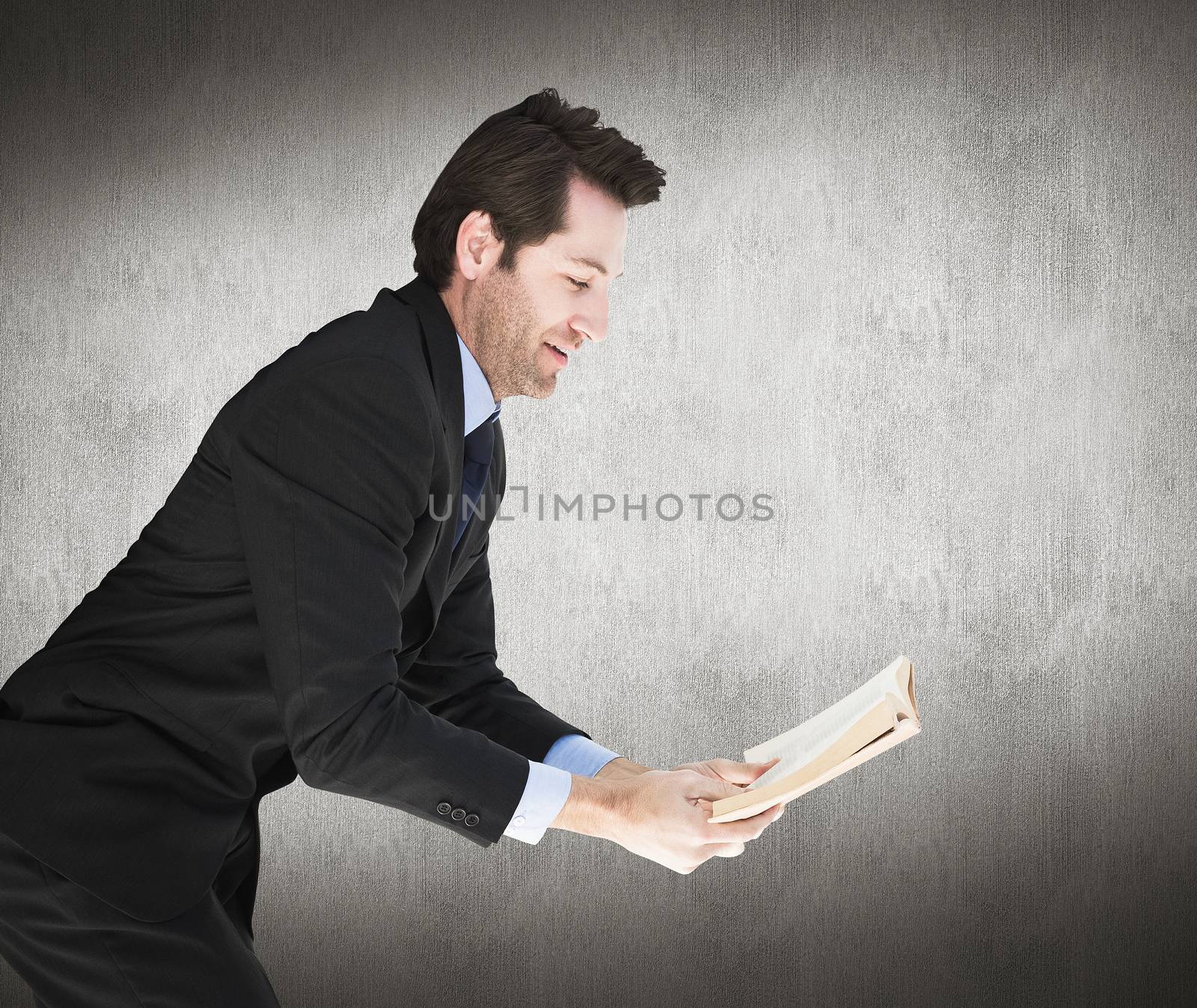 Businessman lying on the floor while reading a book against white and grey background