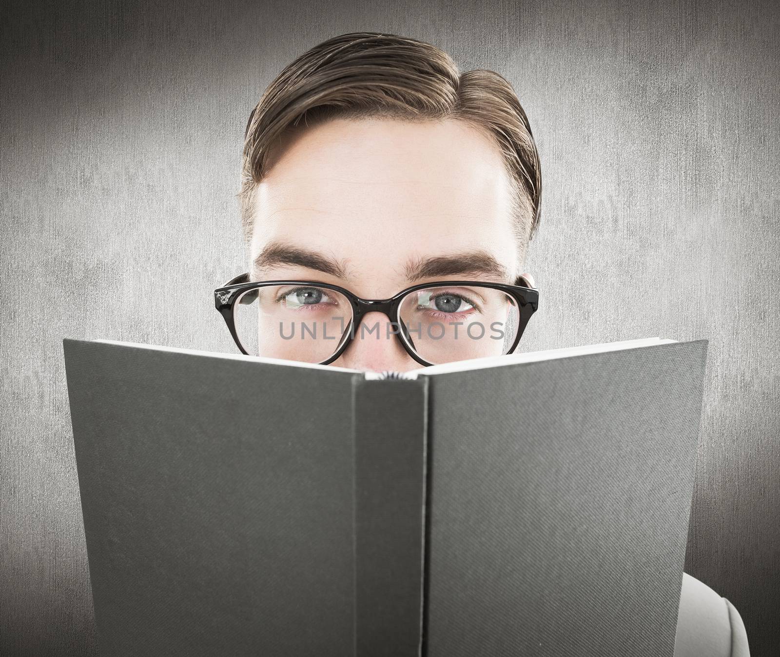 Geeky man looking over book against white and grey background