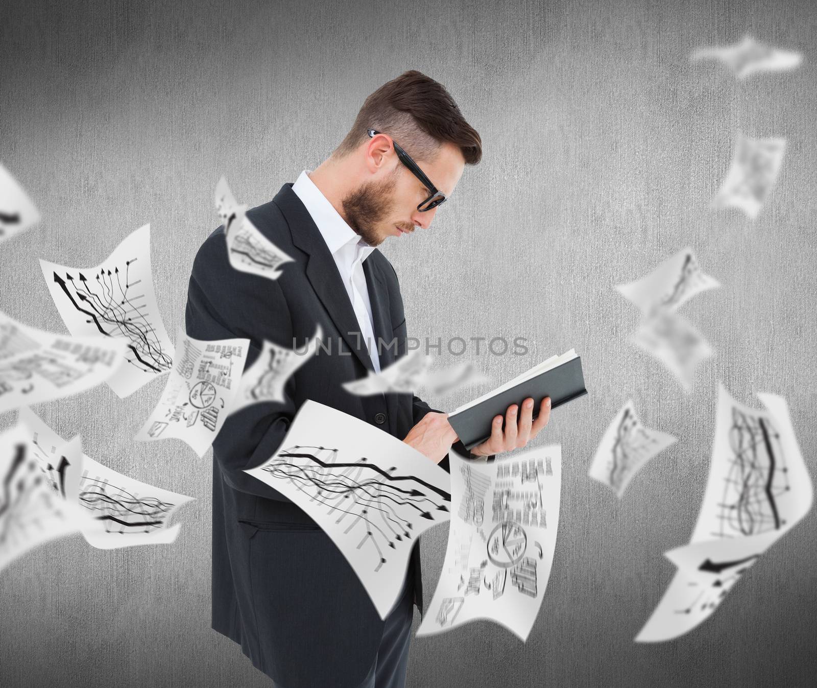 Geeky young man reading from black book against white and grey background