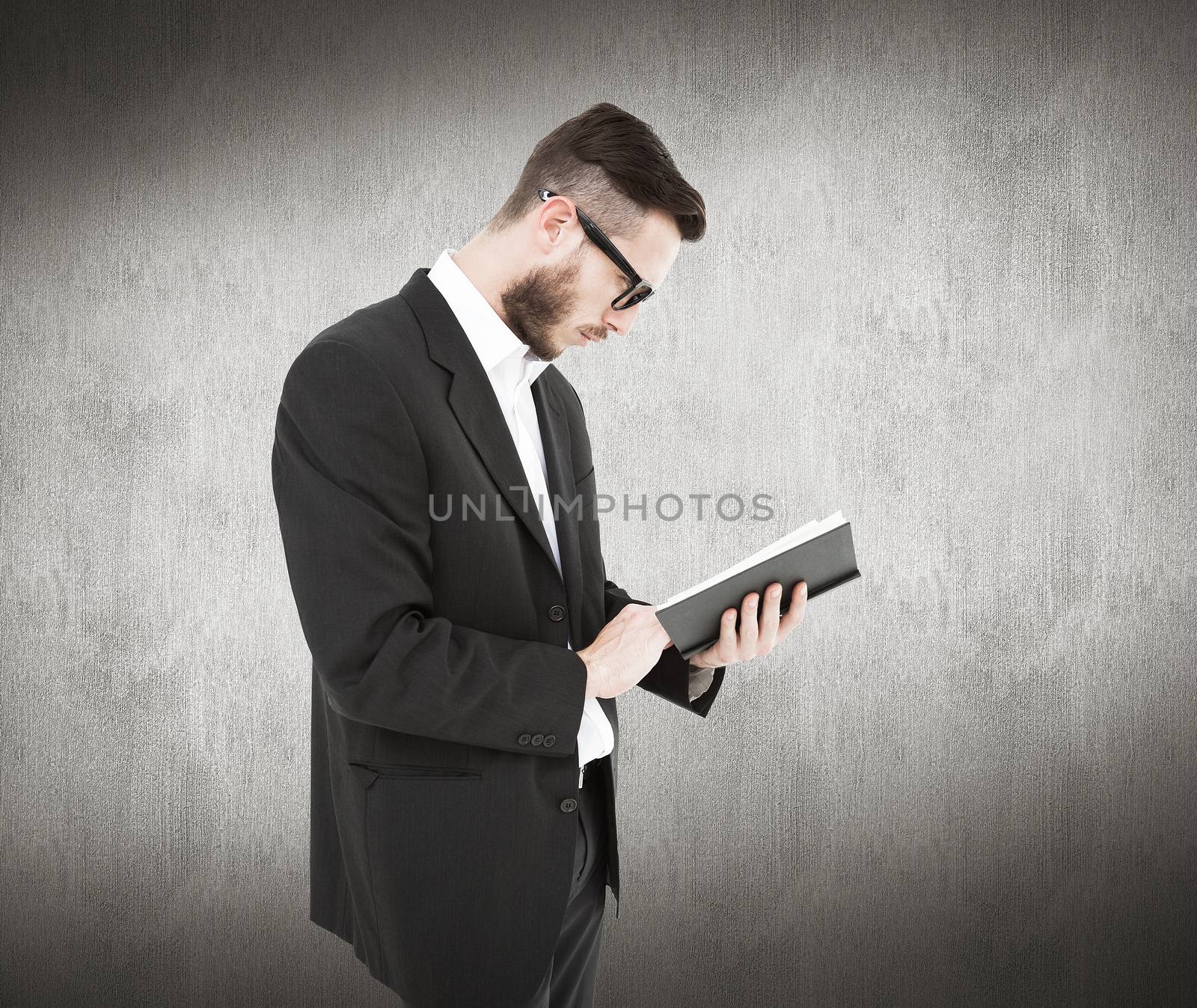 Composite image of geeky young man reading from black book by Wavebreakmedia
