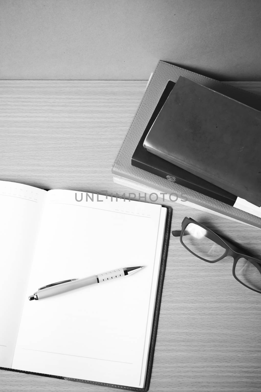 open notebook with stack of book on wood background black and white color tone style