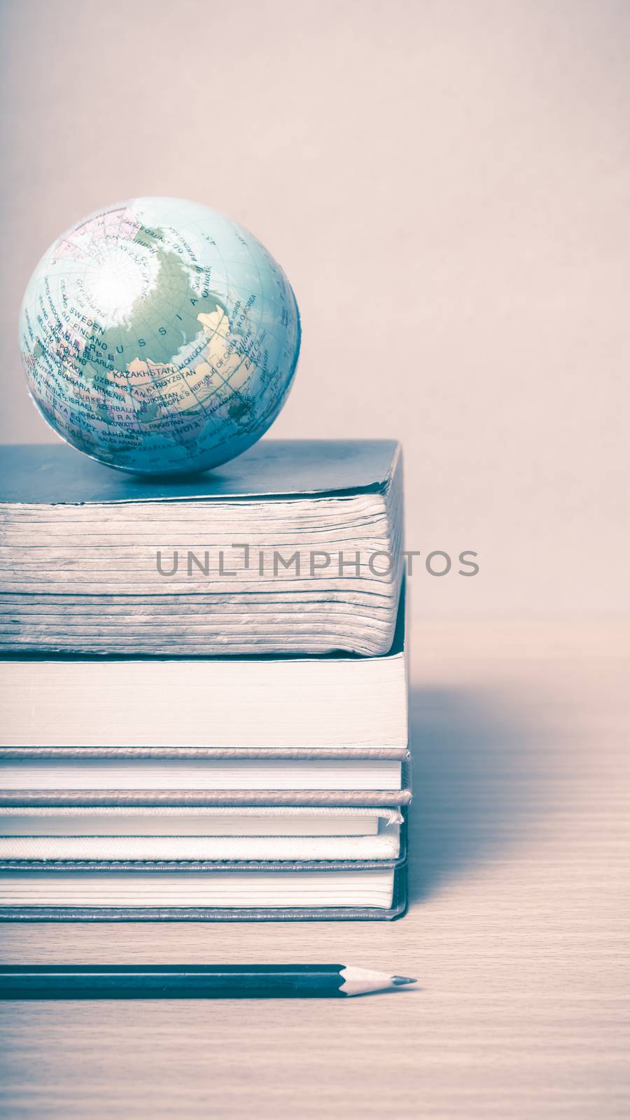 book and earth ball with black pencil on wood background vintage style