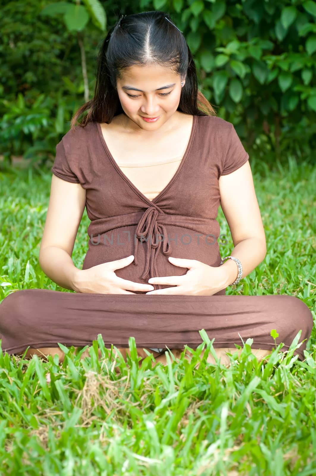 Pregnant woman sitting in the park . in anticipation of the chil by Yuri2012