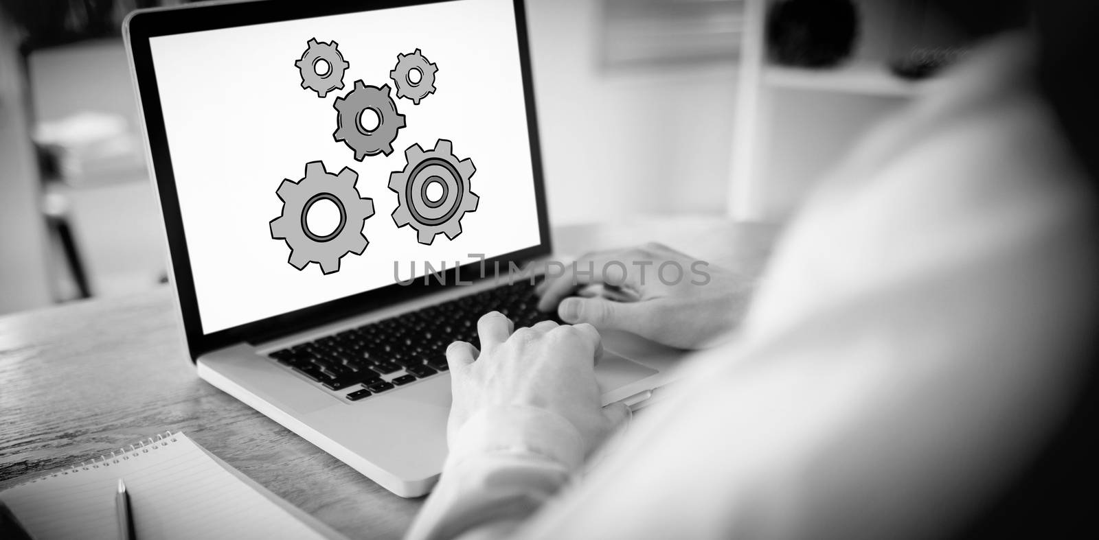 Businessman working on his laptop against cogs