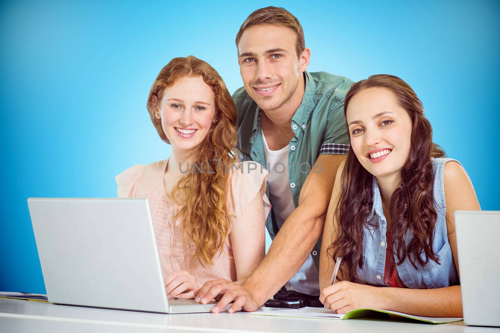 Fashion students using laptop against blue background with vignette