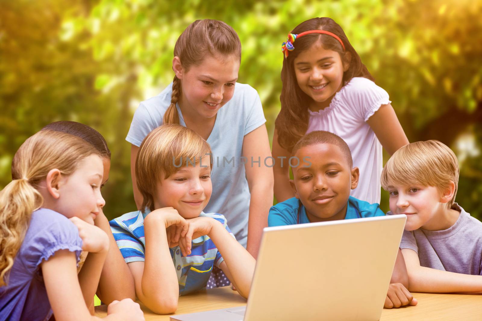 Cute pupils using tablet computer in library against trees and meadow in the park