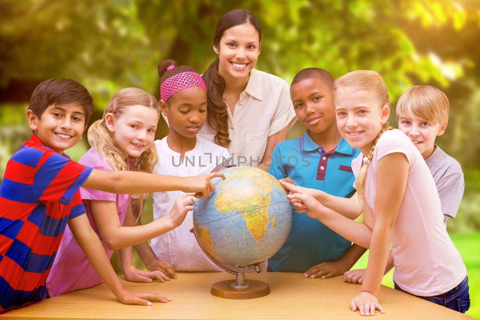 Composite image of cute pupils and teacher looking at globe in library by Wavebreakmedia