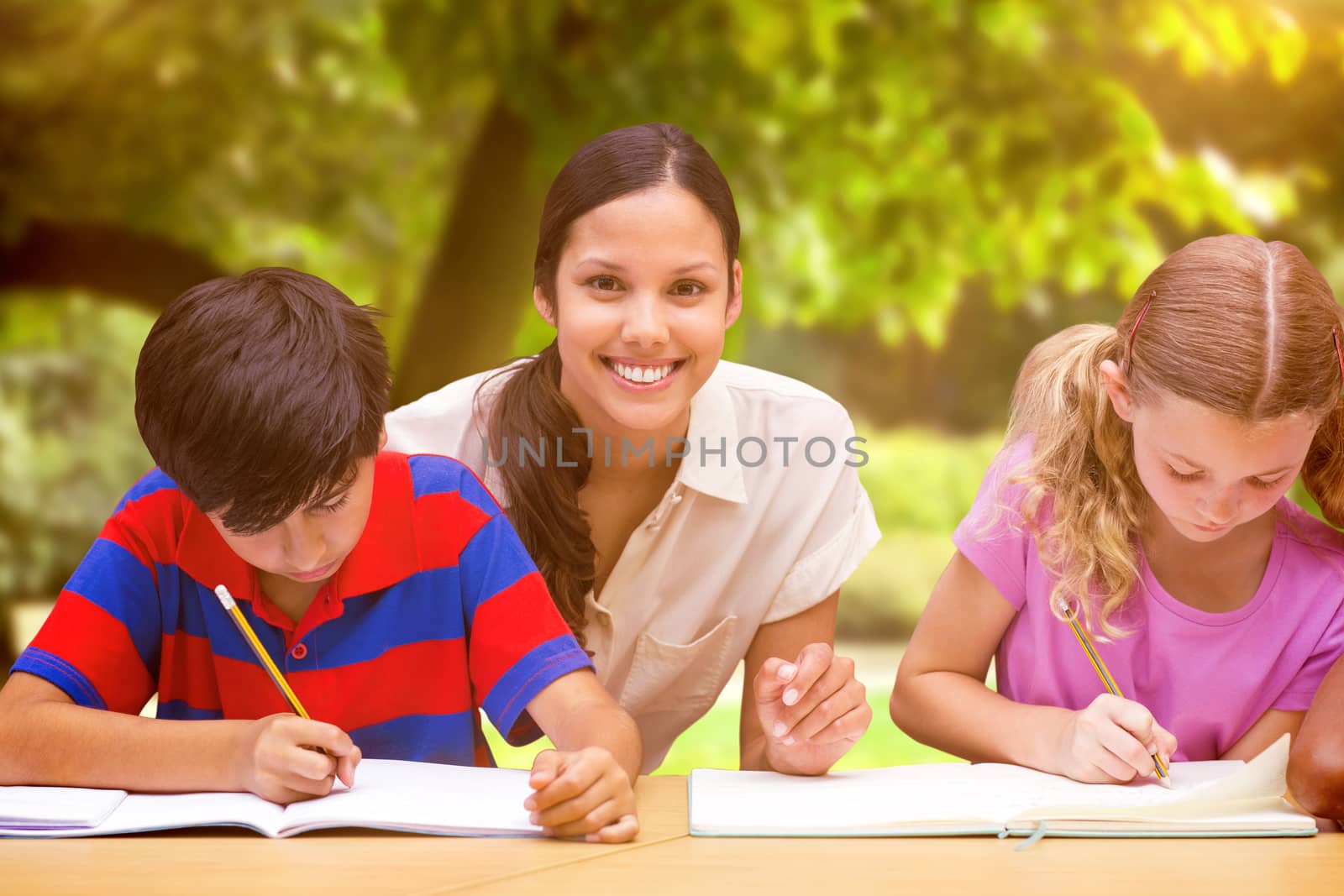 Pretty teacher helping pupils in library against trees and meadow in the park