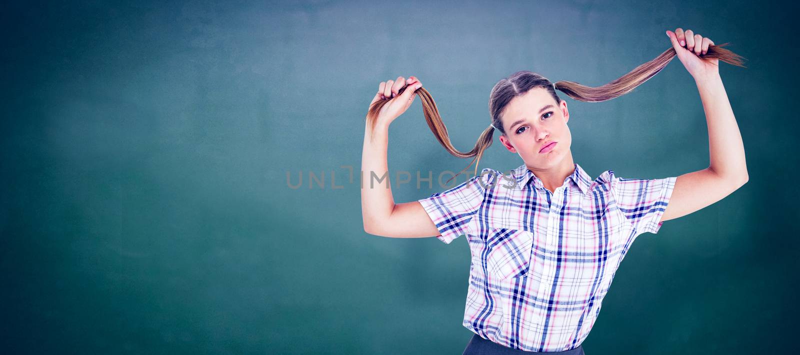 Geeky hipster holding her pigtails against green chalkboard