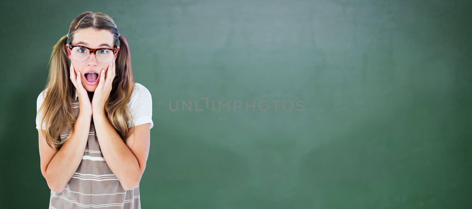 Surprised geeky hipster looking at camera against green chalkboard