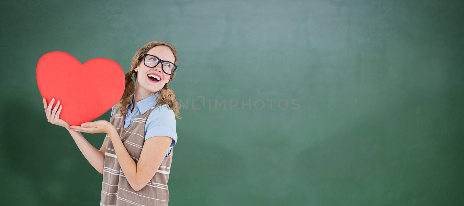 Geeky hipster woman holding heart card against green chalkboard