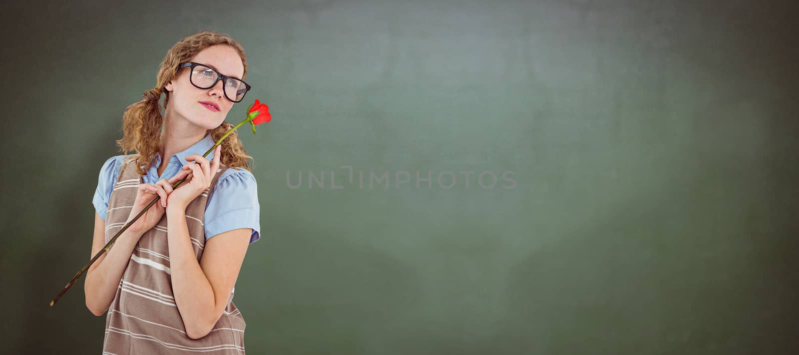 Geeky hipster woman holding rose  against green chalkboard