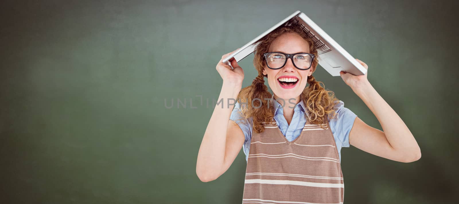 Geeky hipster woman covering her head with her laptop  against green chalkboard