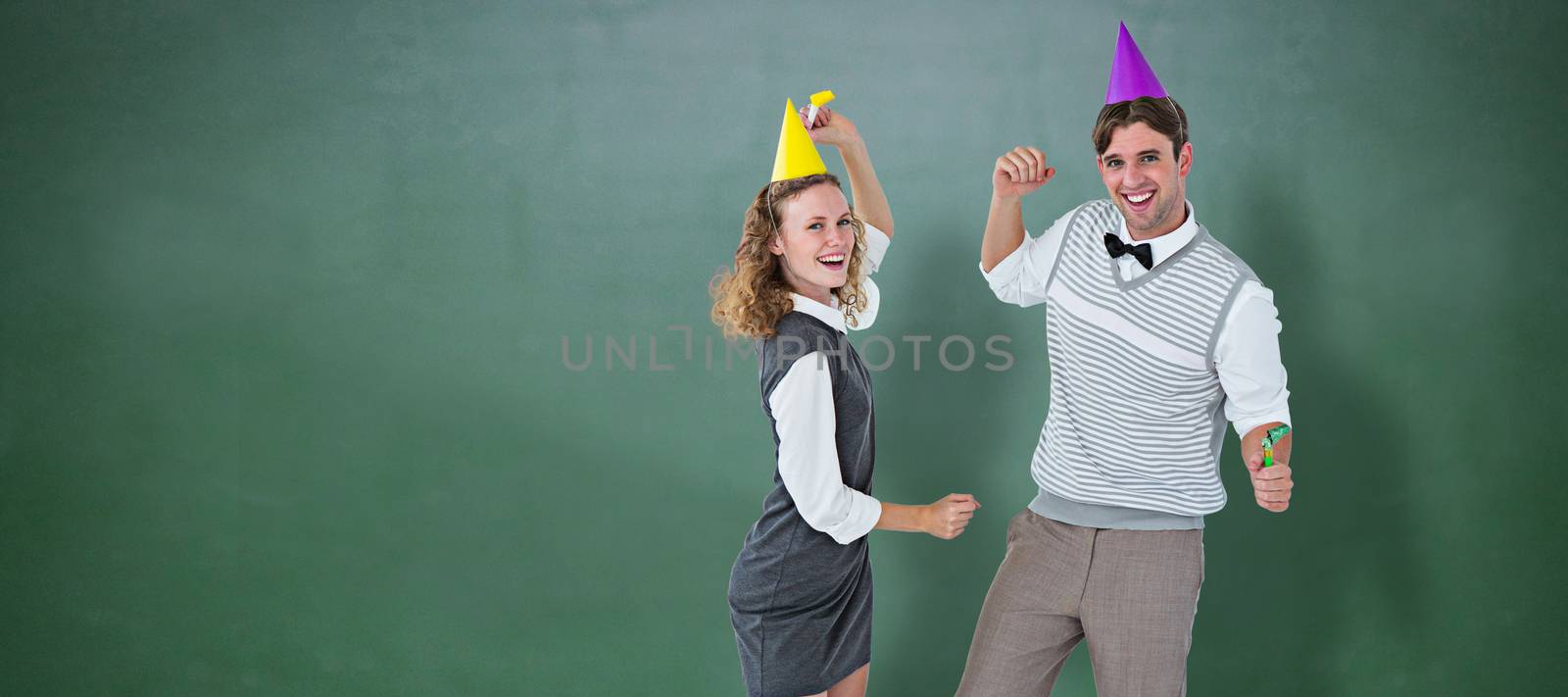 Geeky couple dancing with party hat  against green chalkboard