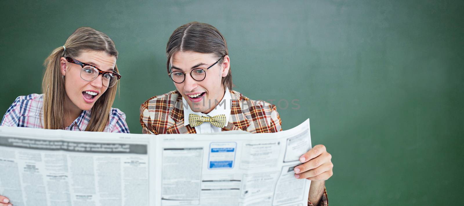 Geeky hipsters reading the newspaper against green chalkboard