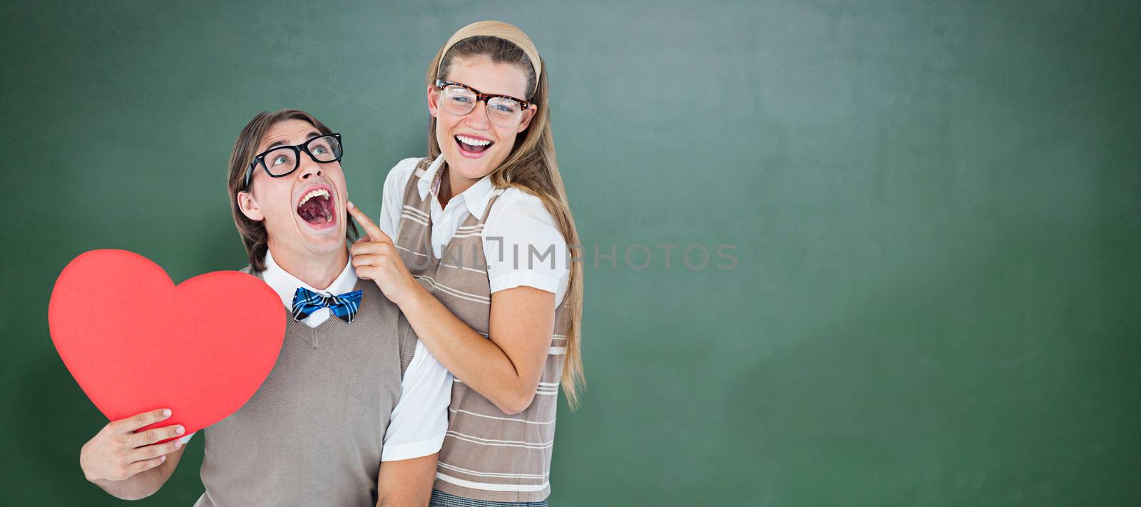 Excited geeky hipster and his girlfriend  against green chalkboard