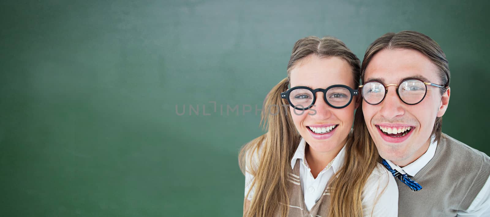 Geeky hipsters smiling at camera  against green chalkboard