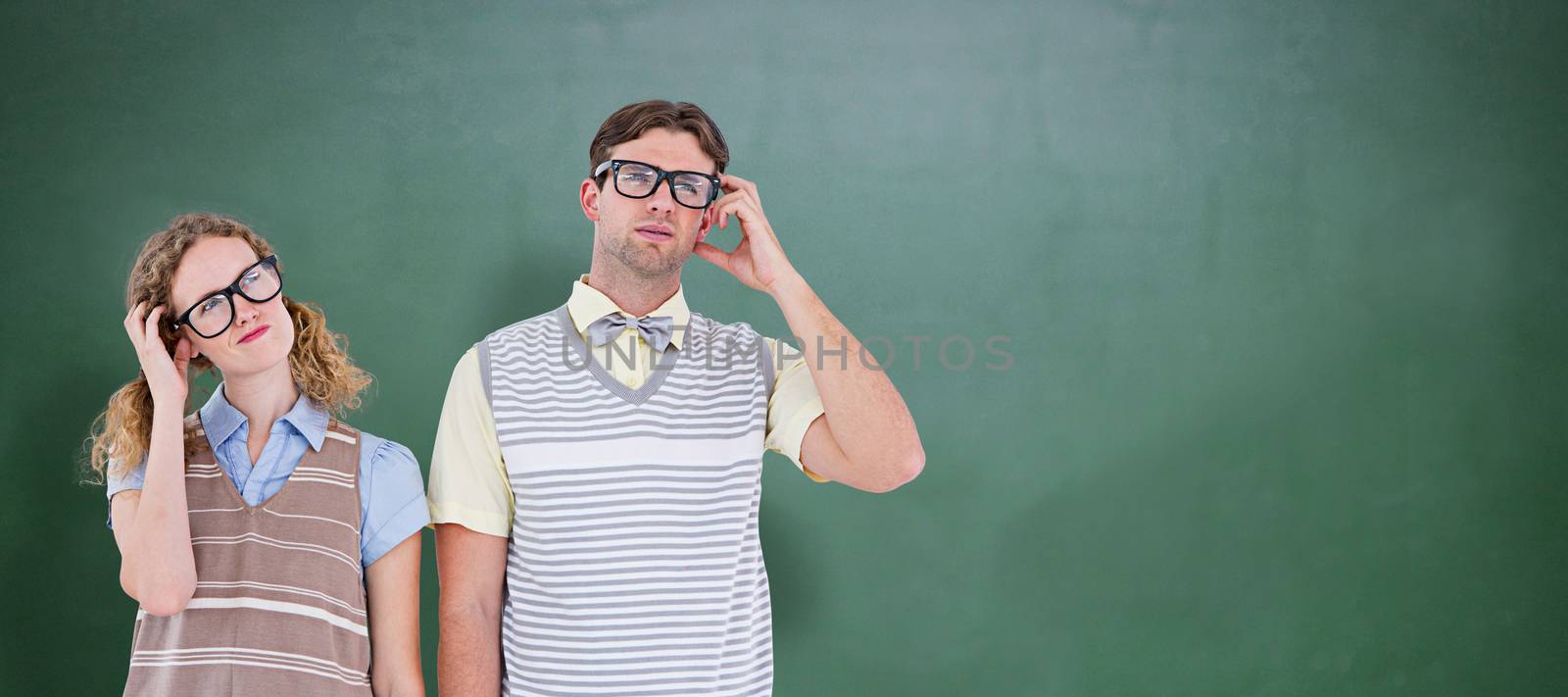 Geeky hipster couple thinking with hand on temple against green chalkboard