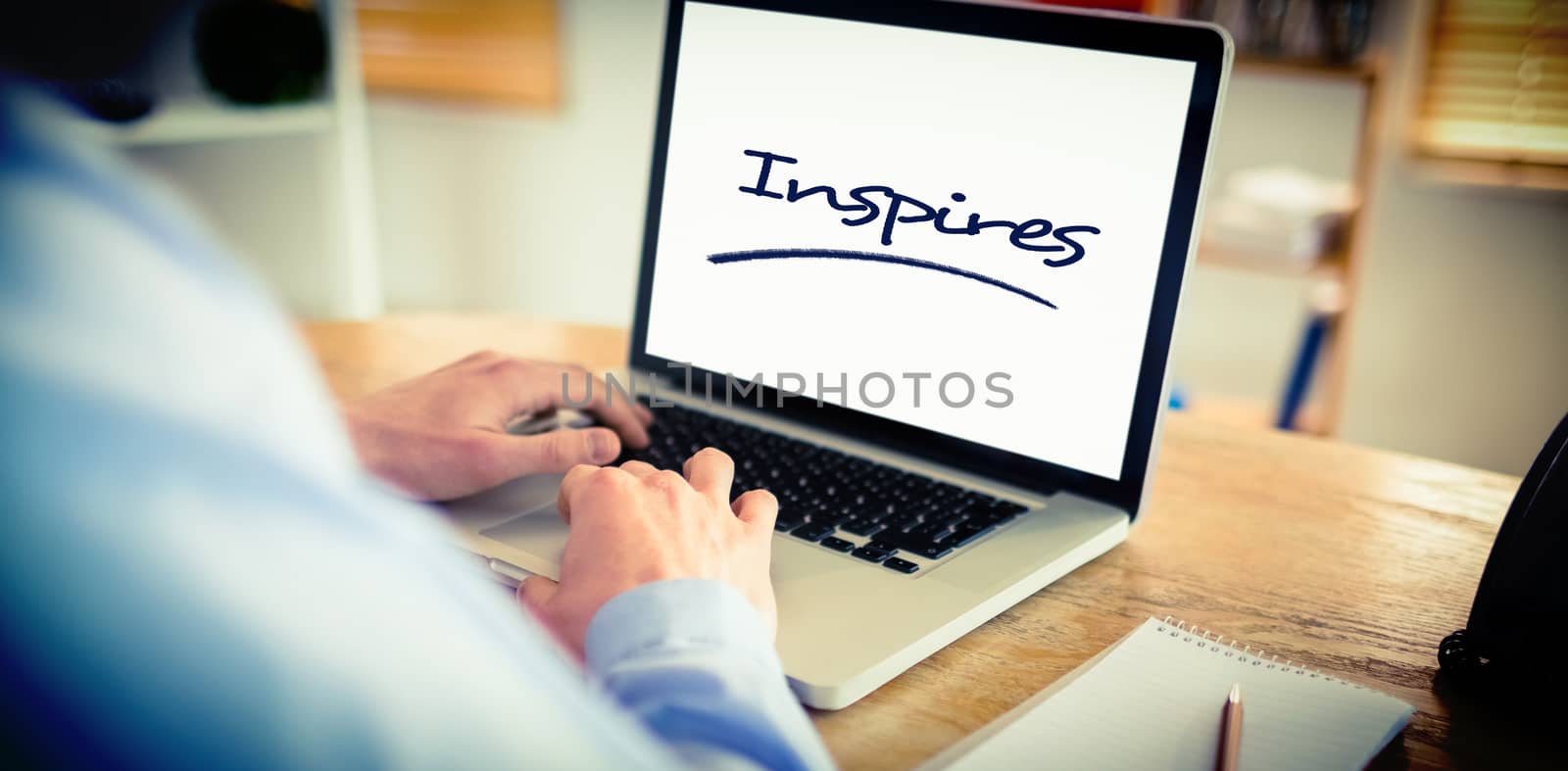 The word inspires against businessman working on his laptop