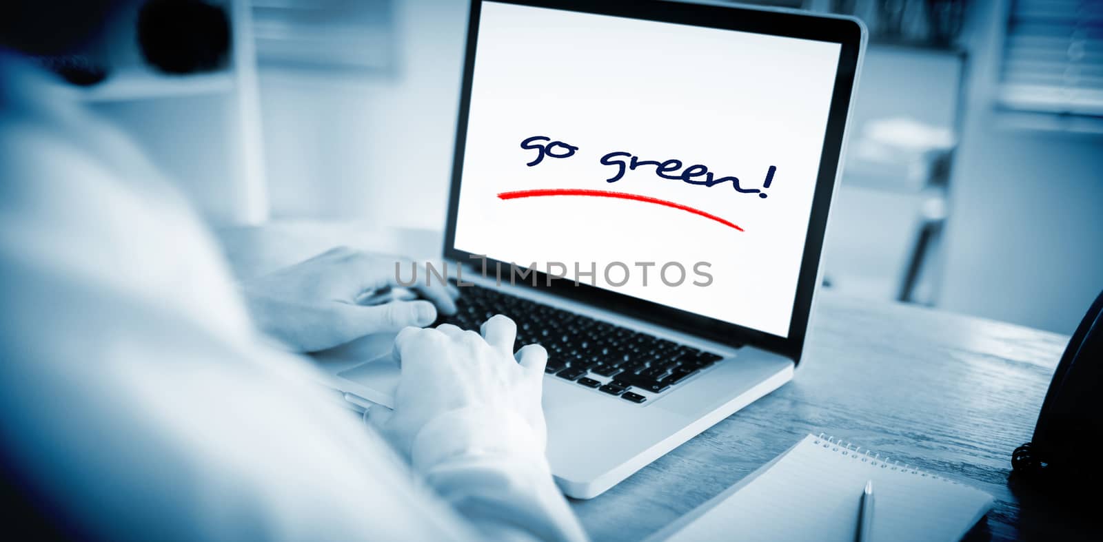 The word go green! against businessman working on his laptop