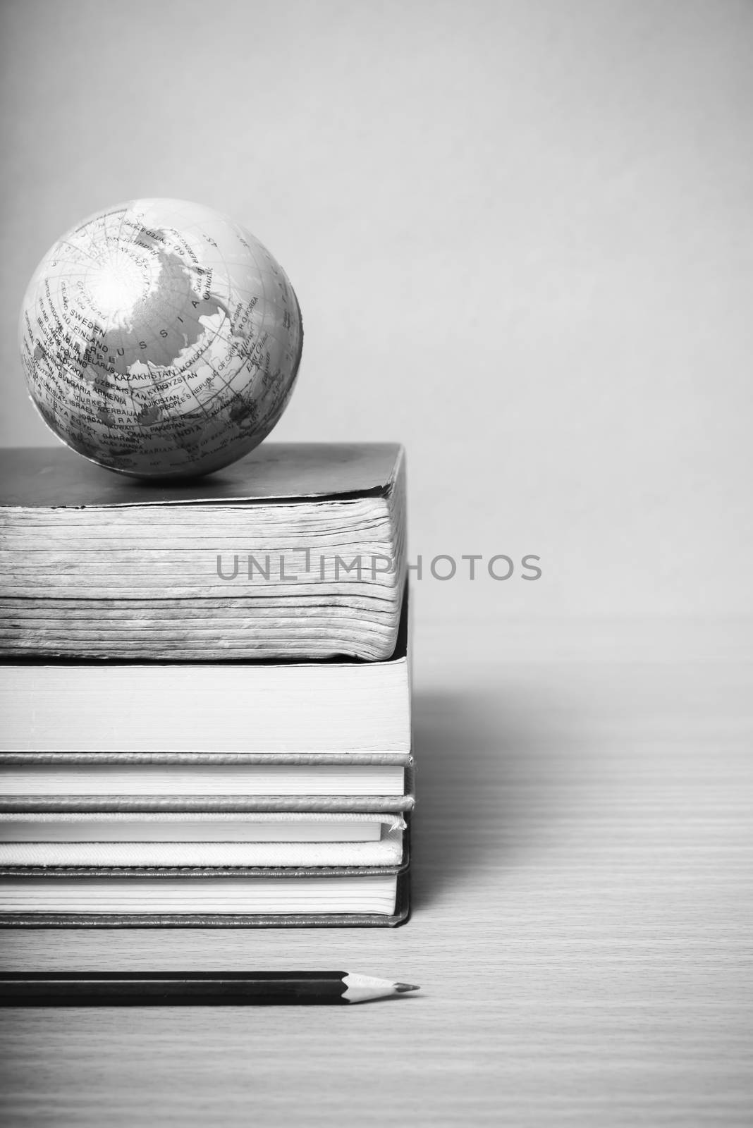 book and earth ball with black pencil on wood background black and white color tone style