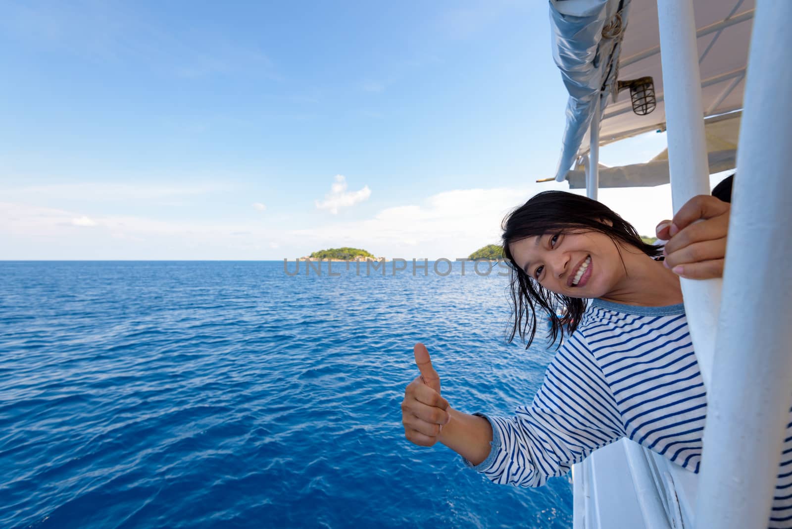 Tourist woman smiling happily with thumb up praising the beautiful of the sea at Mu Koh Similan island National Park, Phang Nga Province, Thailand
