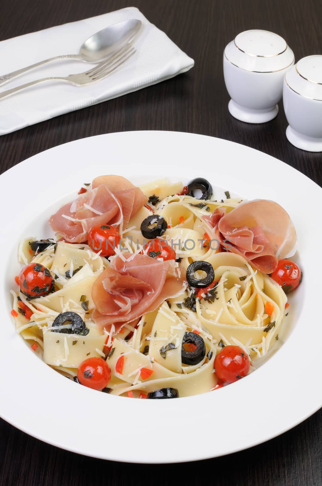 plate of spaghetti with jamon, tomatoes, olives and parmesan