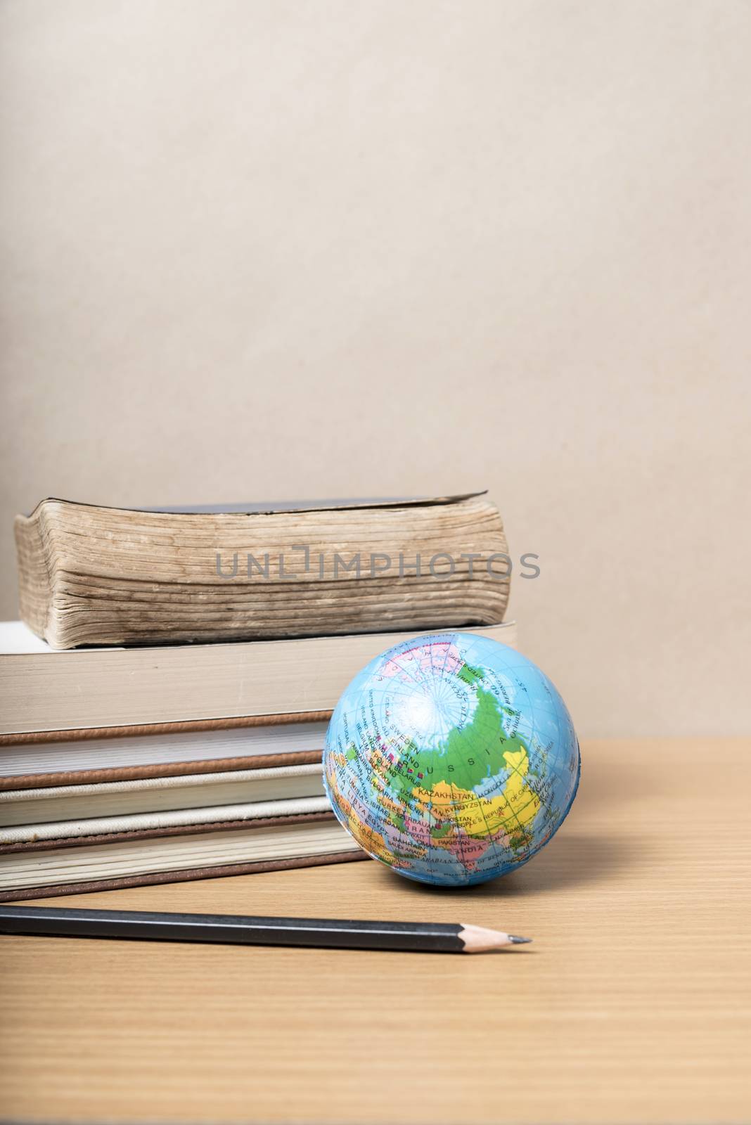 book and earth ball with black pencil on wood background