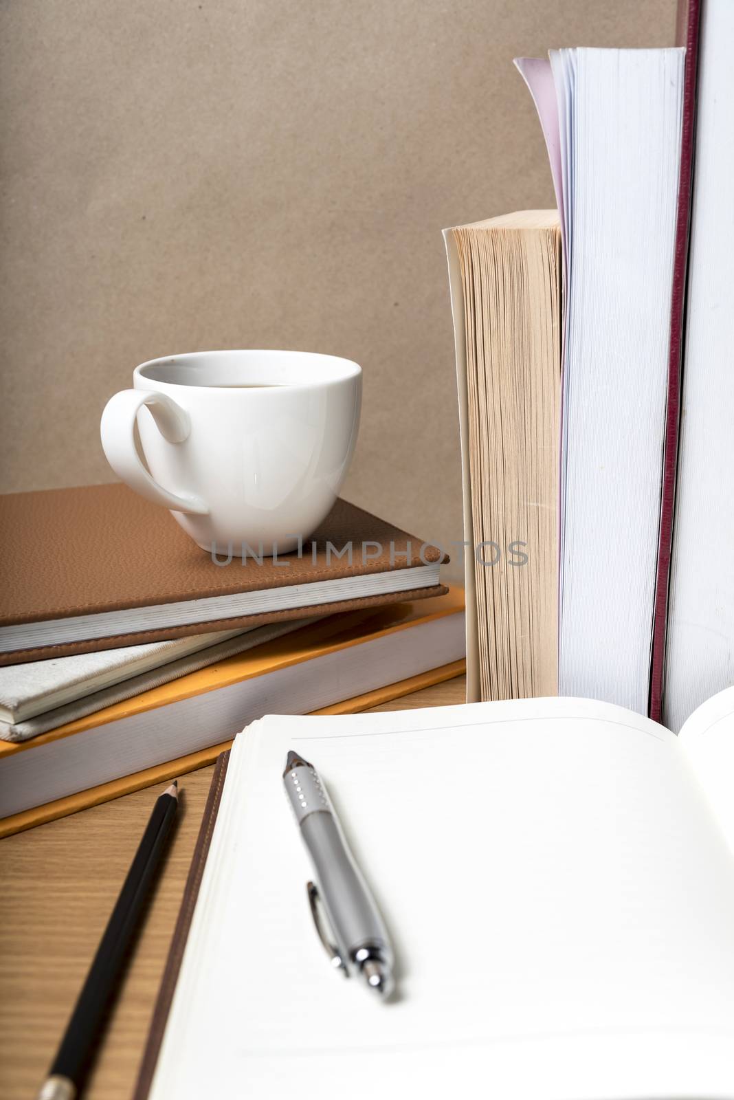 open notebook with book and coffee cup on wood background