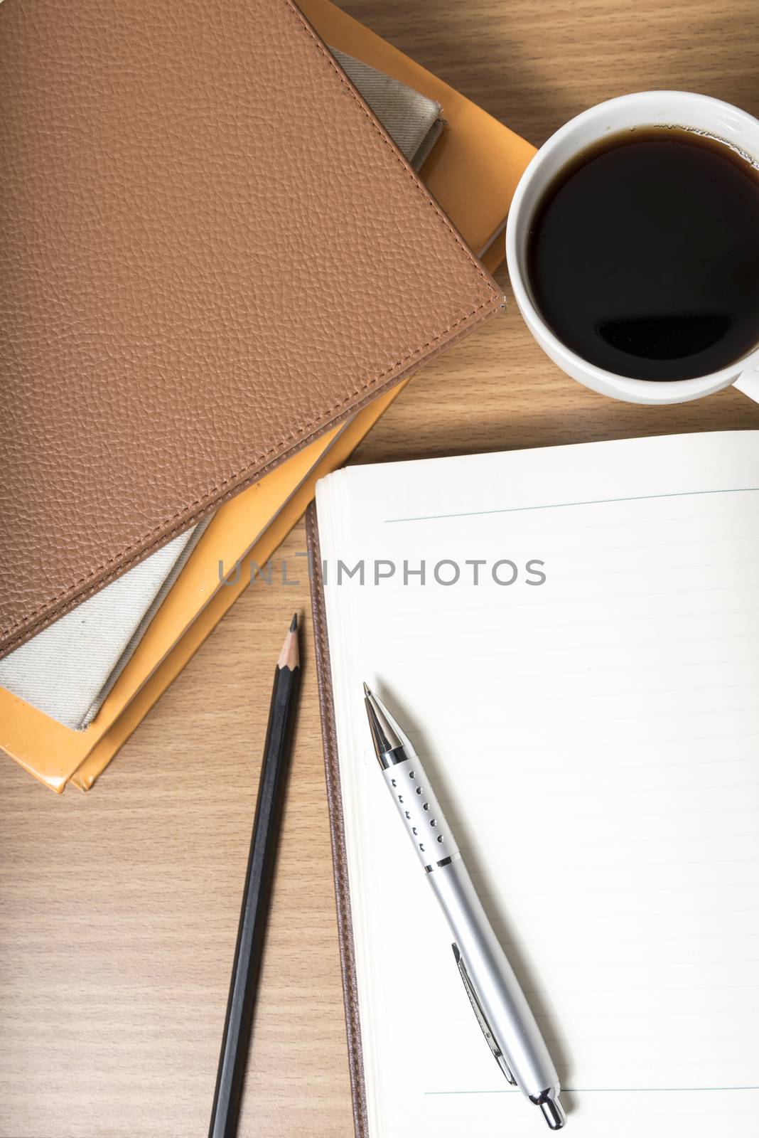 open notebook with book and coffee cup on wood background