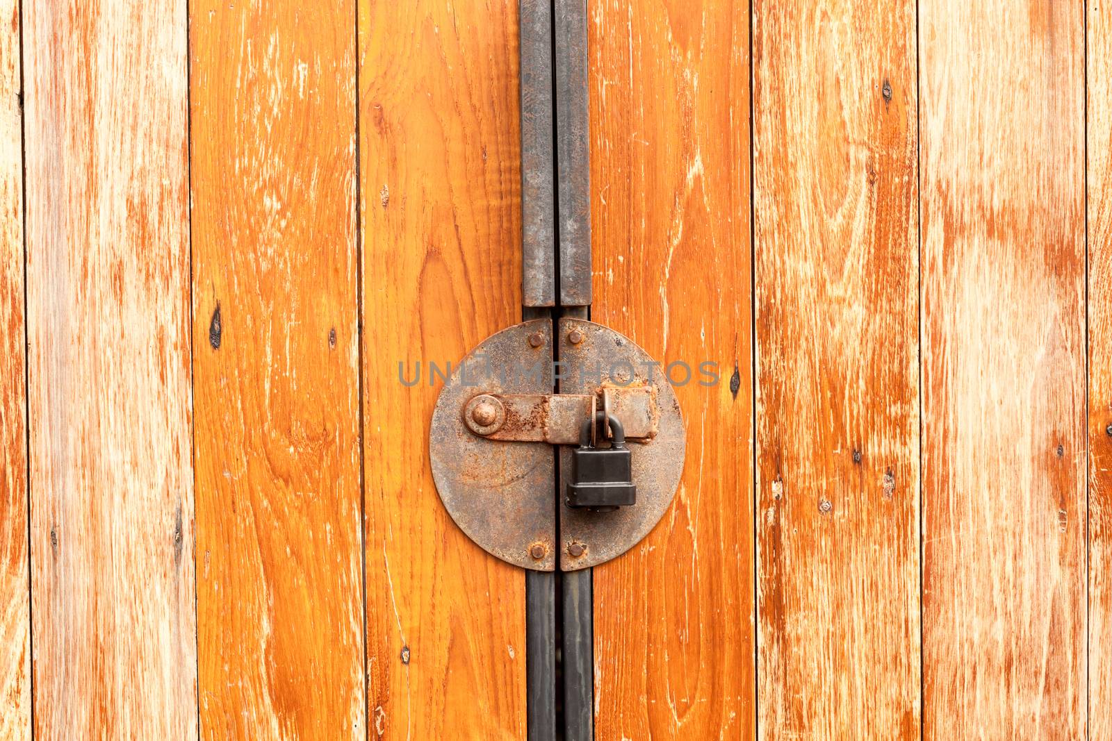 Old rusty with padlock on a wooden door by nopparats