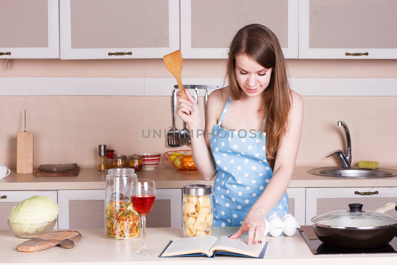 Girl in a blue apron in the kitchen preparing