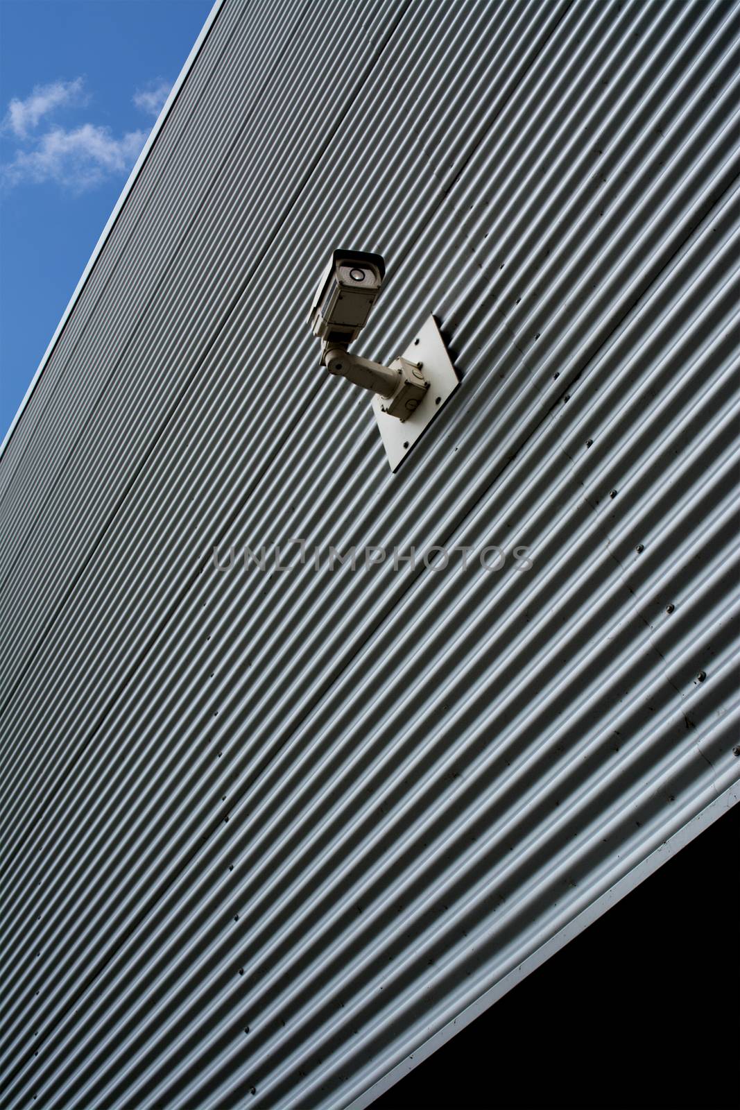 Security camera on a striped plated wall.