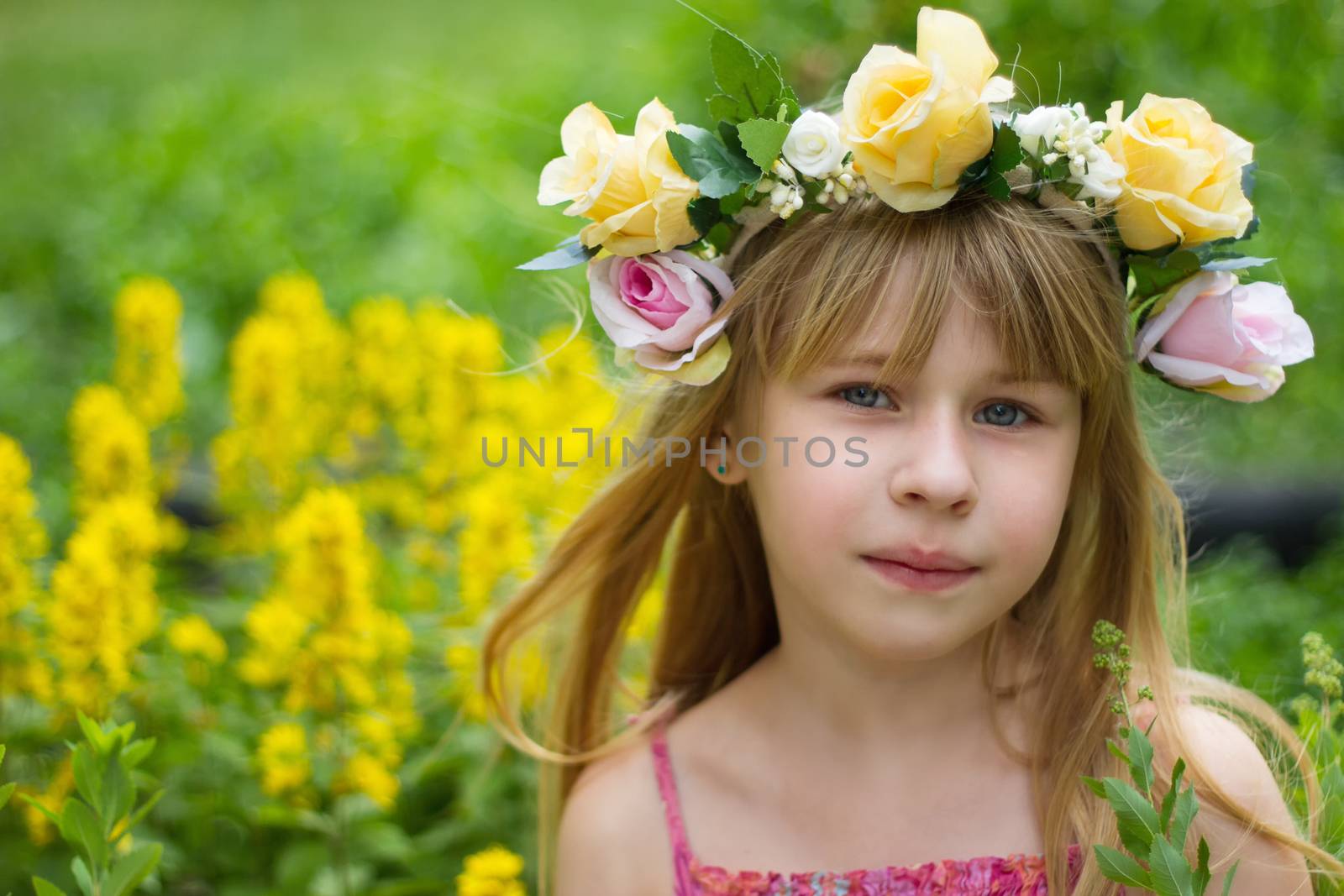 Girl 6 years old in a wreath in the meadow.  Horizontal framing