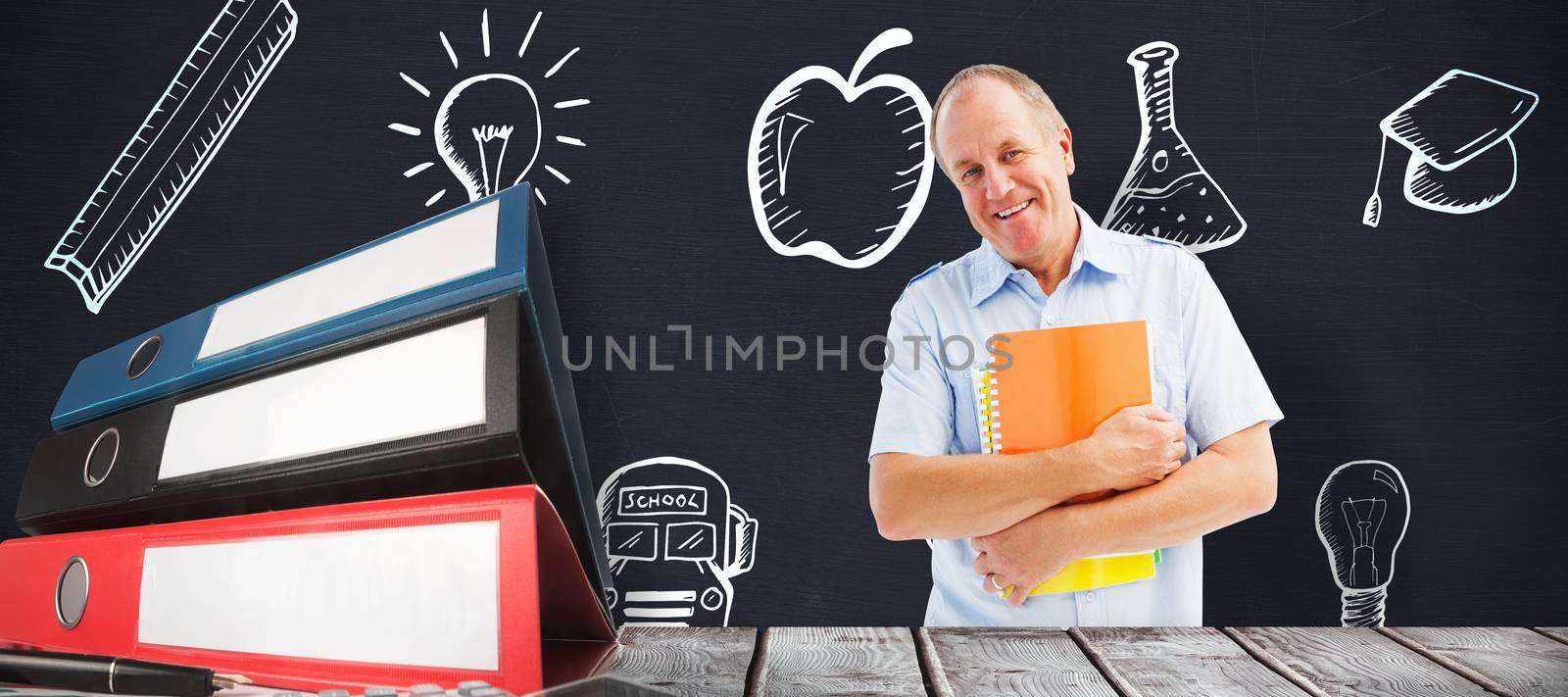 Mature student holding notebooks against blackboard