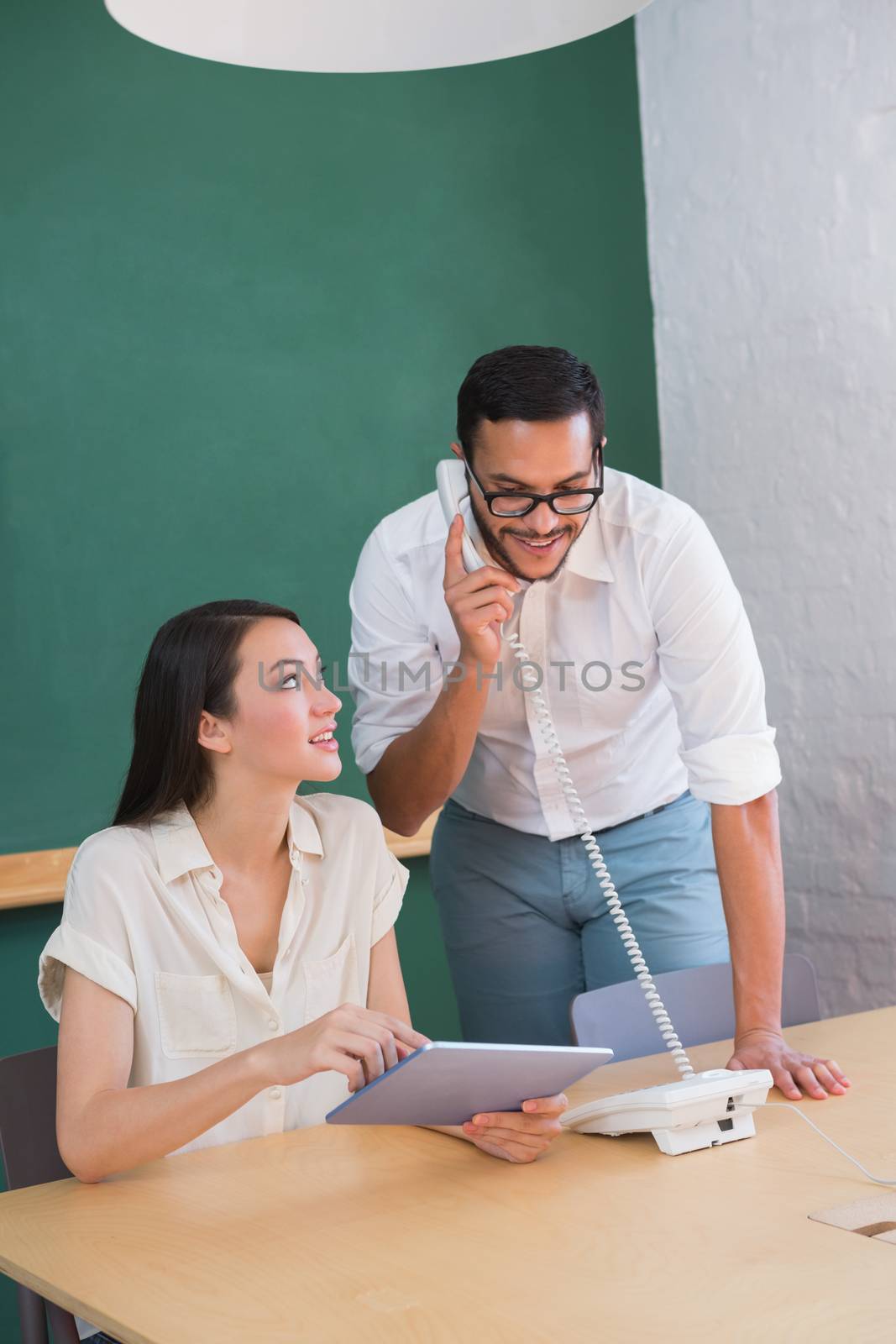 Two casual business people using digital tablet and telephone