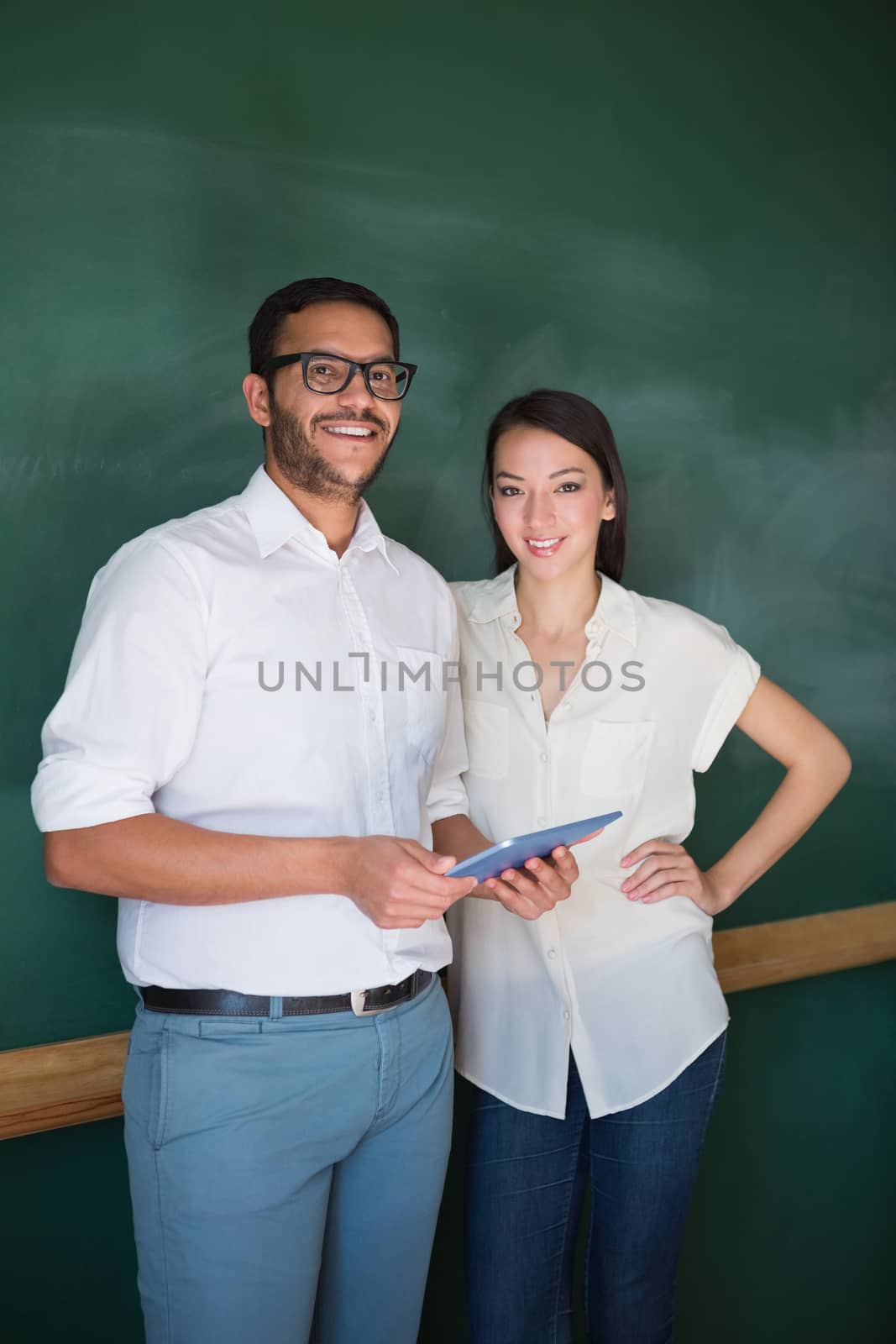 Portrait of two confident young business people with digital tablet in office