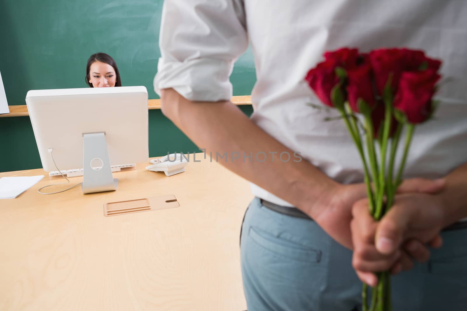 Man hiding bouquet in front of businesswoman at desk by Wavebreakmedia