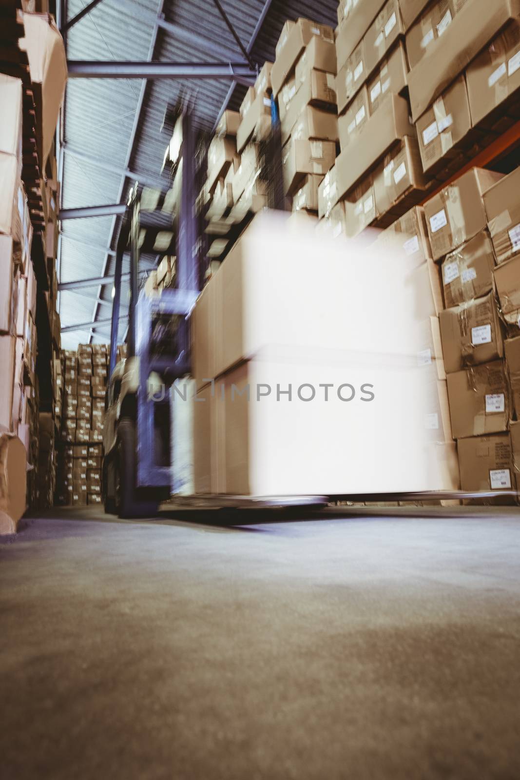 Forklift amid rows of shelves with boxes in large warehouse