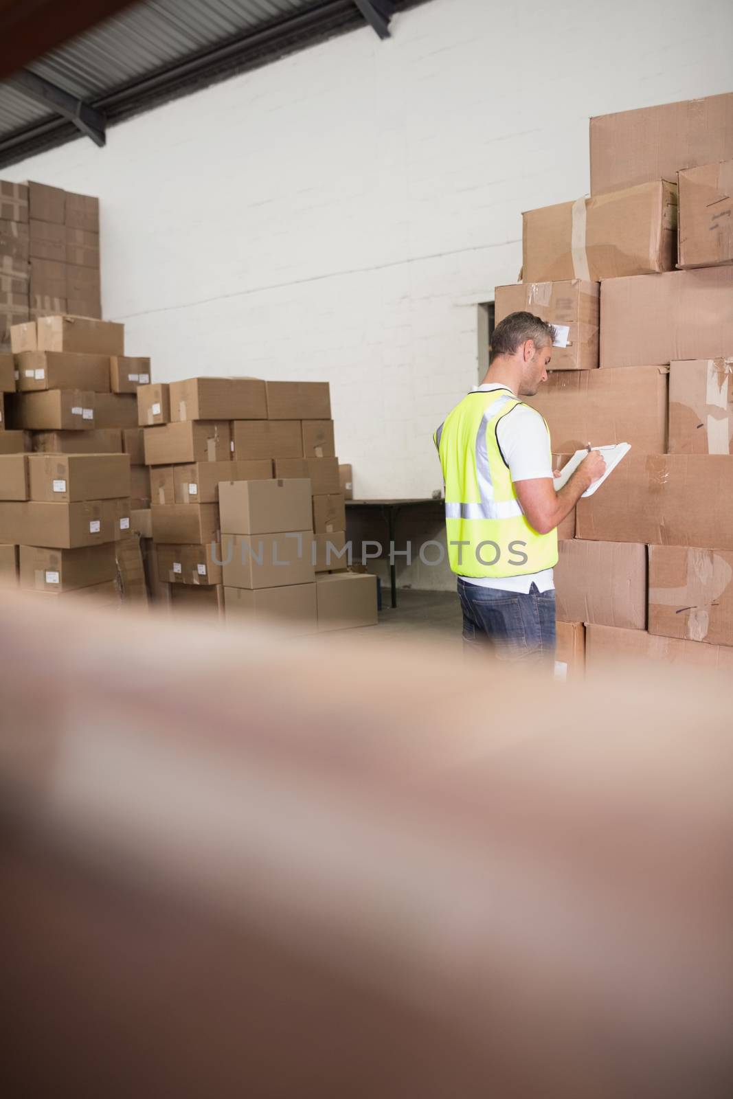 Warehouse worker with clipboard by Wavebreakmedia