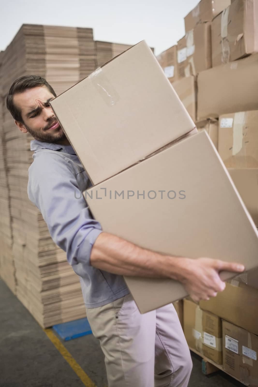 Side view of worker carrying boxes in the warehouse