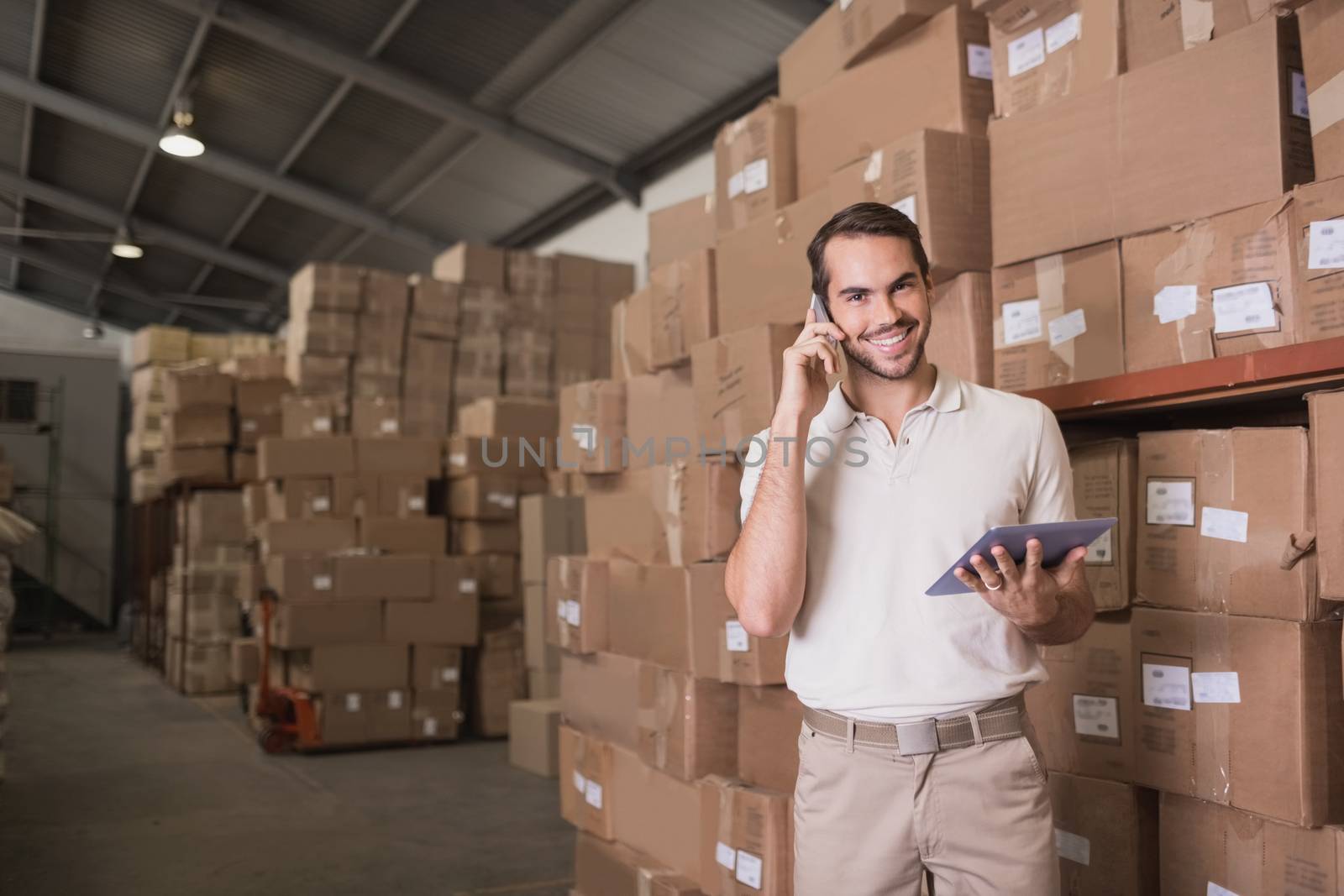 Worker with mobile phone and digital tablet in warehouse by Wavebreakmedia