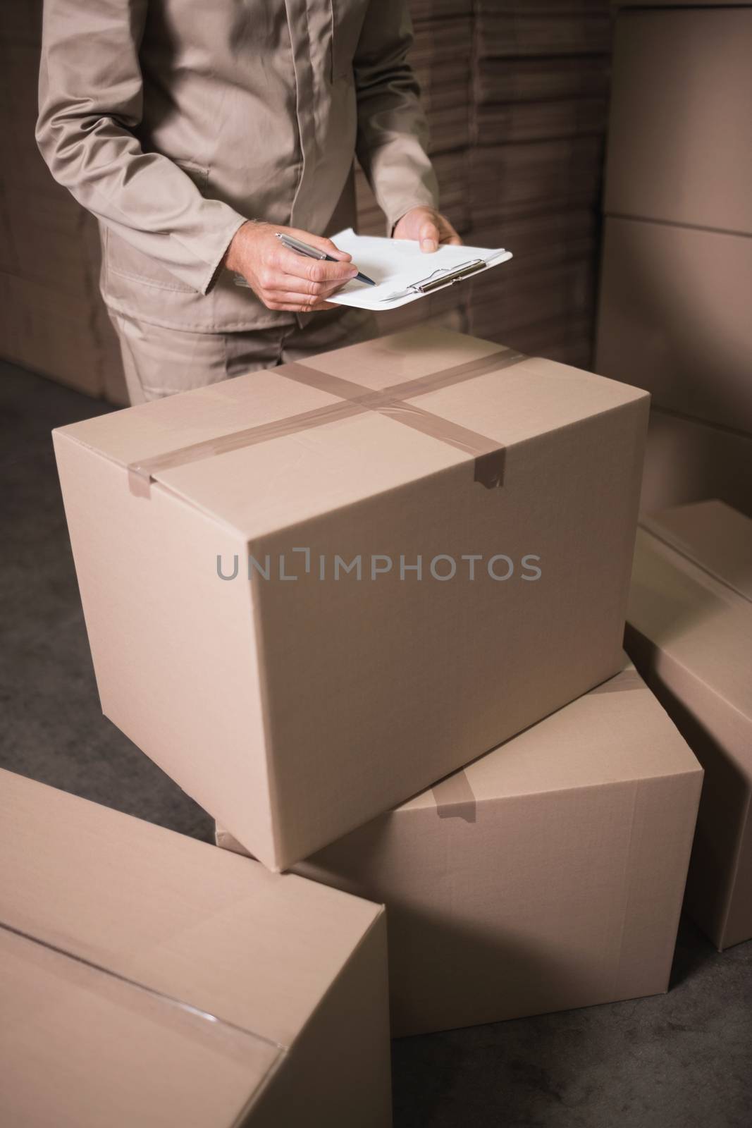 Mid section of warehouse worker with clipboard by Wavebreakmedia