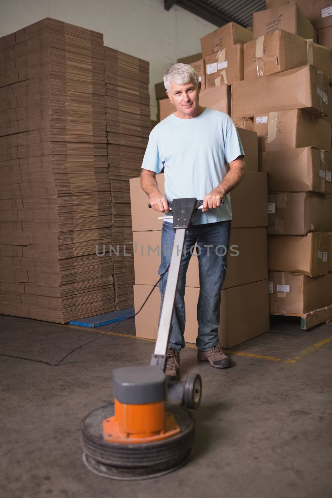 Portrait of man cleaning warehouse floor with machine