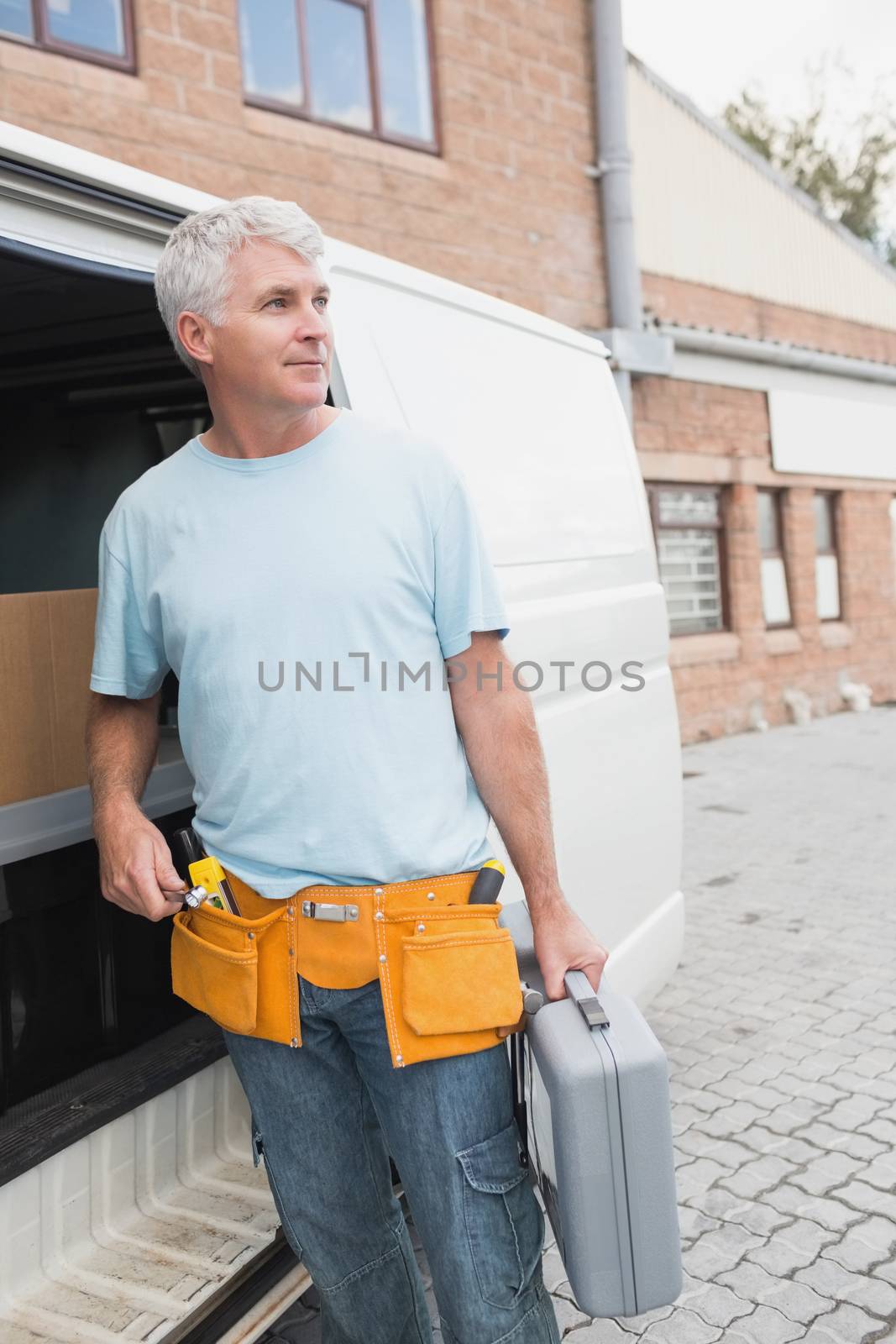 Man with tool belt and briefcase by van by Wavebreakmedia