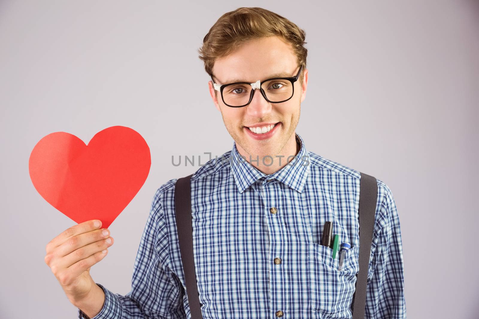 Geeky hipster holding a heart card on grey background