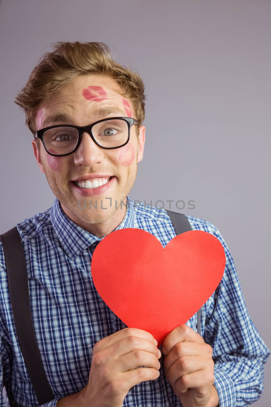 Geeky hipster covered in kisses on grey background