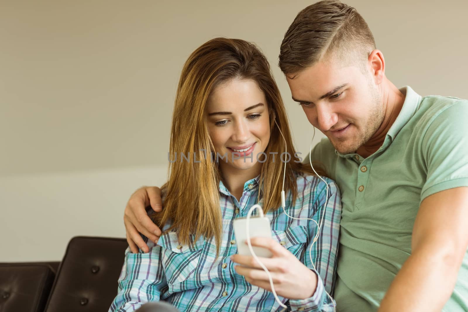 Cute couple relaxing on couch with smartphone by Wavebreakmedia