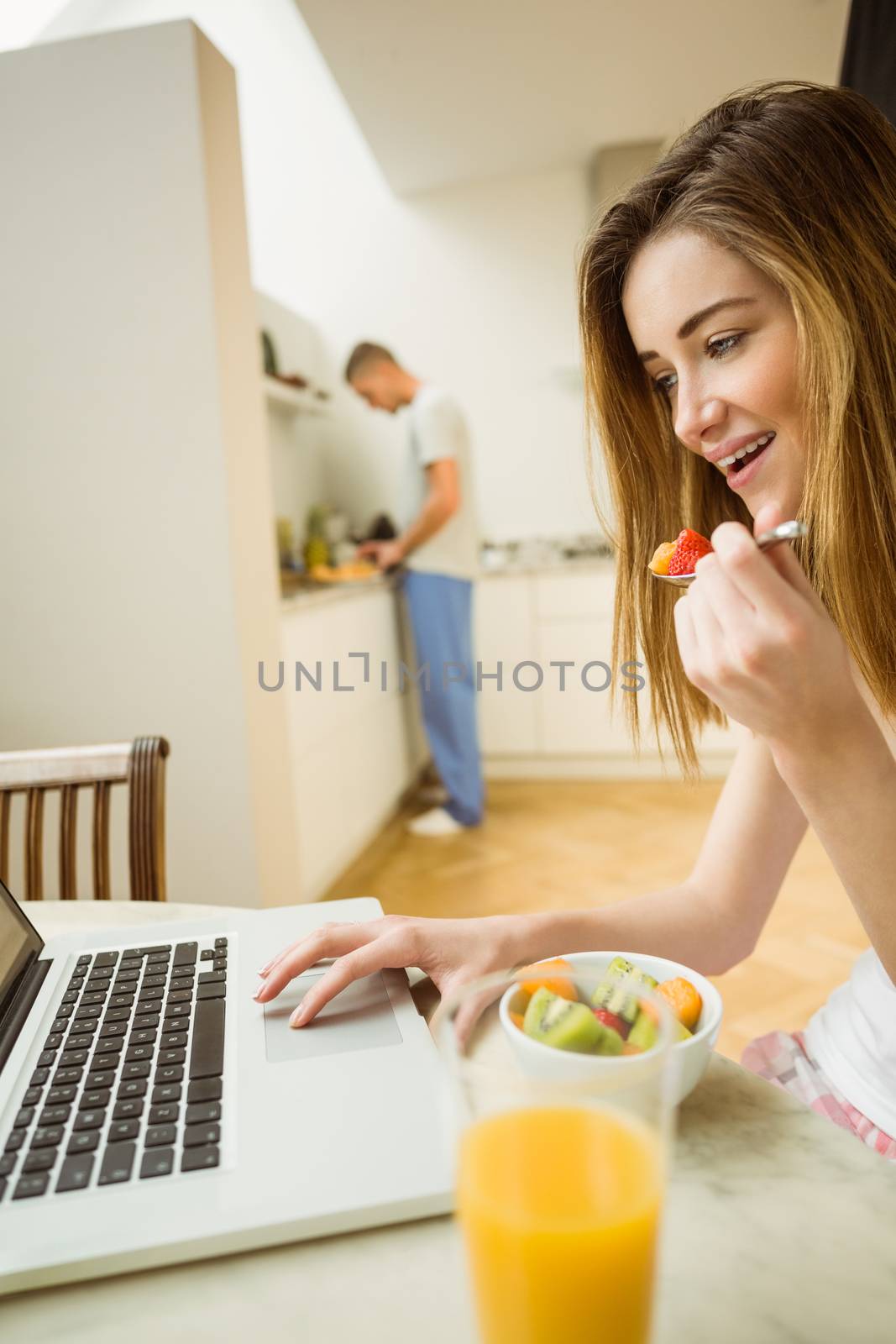 Woman eating fruit salad at breakfast at home in the kitchen