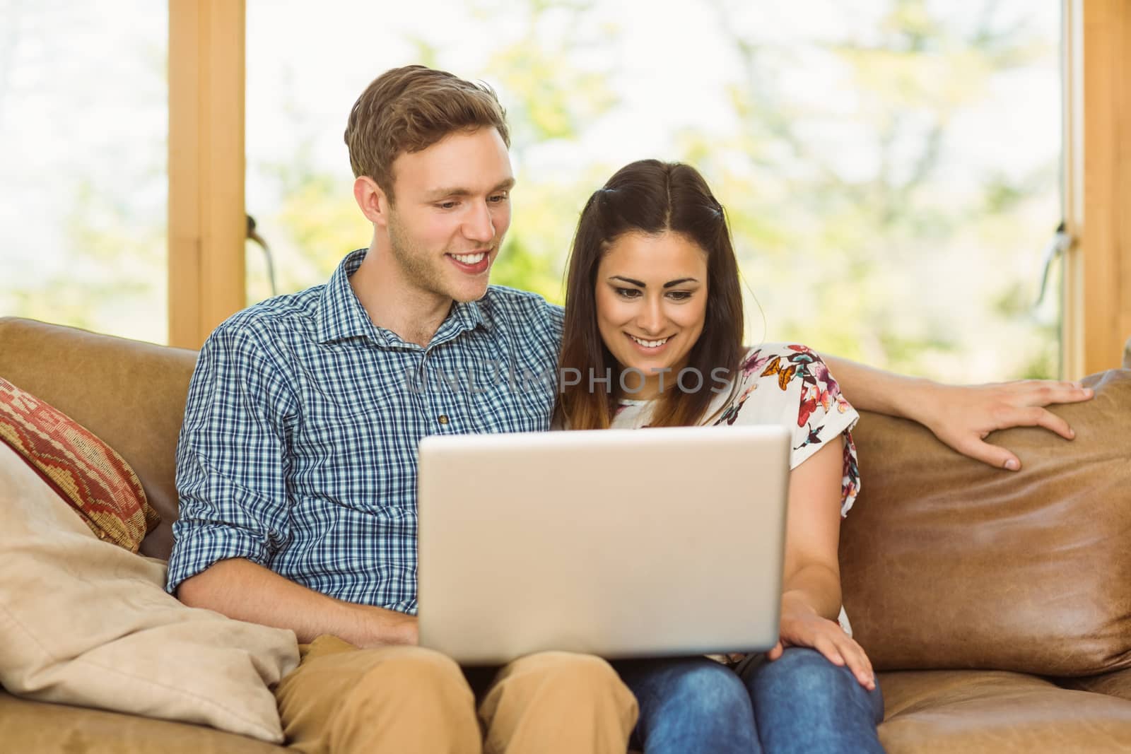 Young cute couple relaxing on couch with laptop at home in the living room